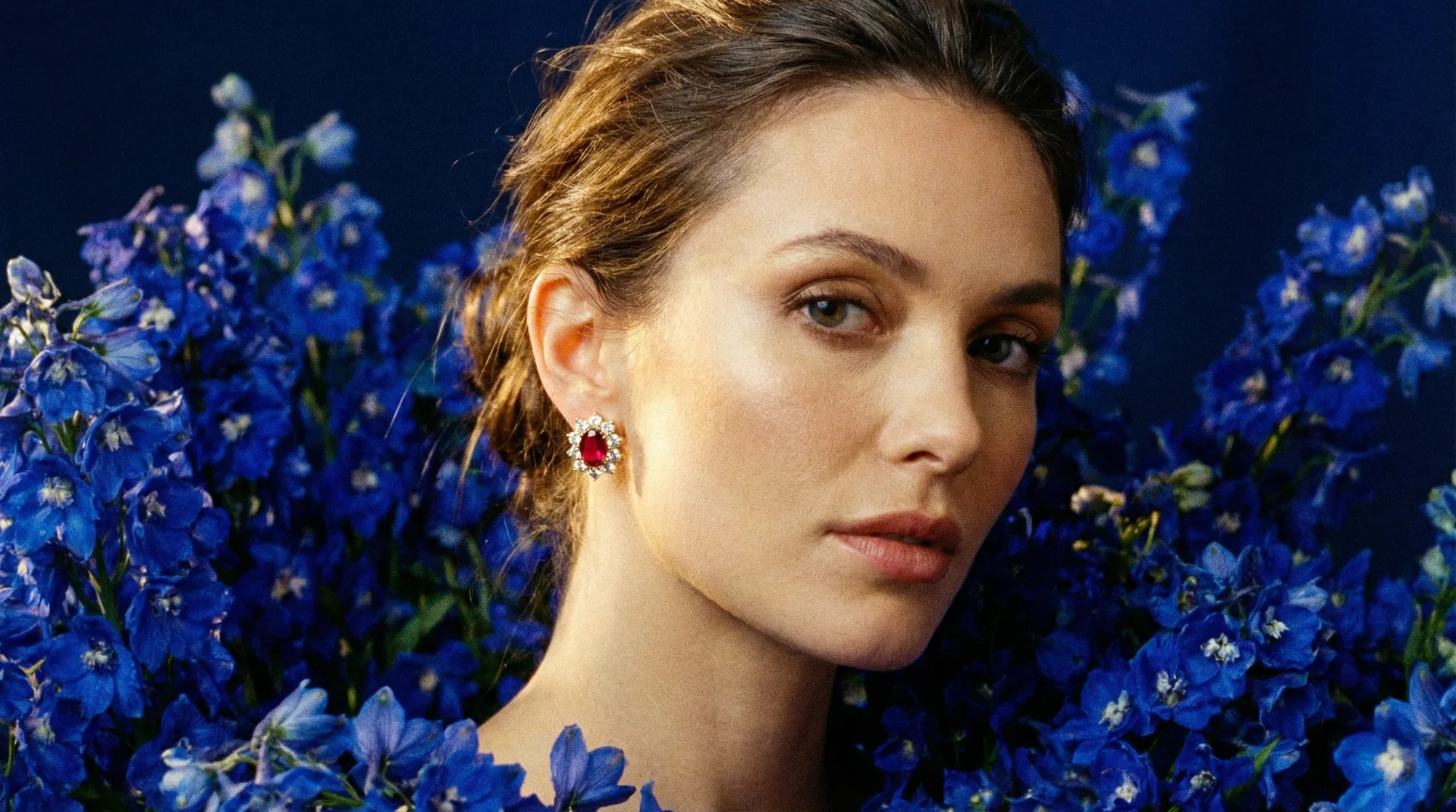 Model wearing bespoke Black Rose jewellery among blue delphiniums